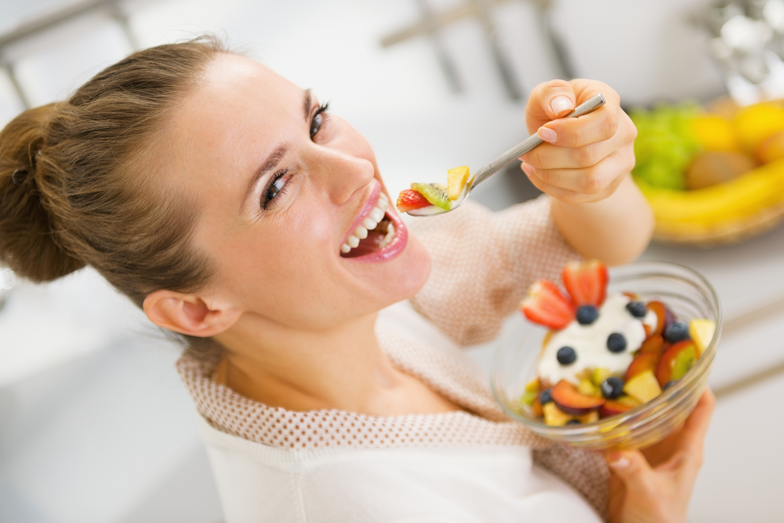 Happy Young Housewife Eating Fruits Salad . Rear View